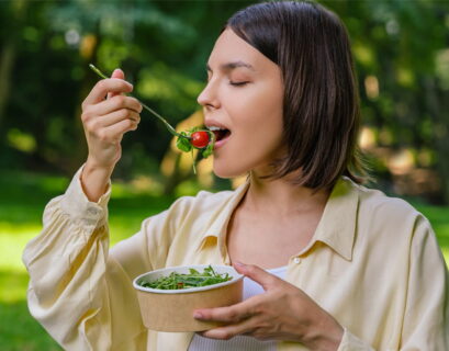 Mujer comiendo una ensalada en la naturaleza